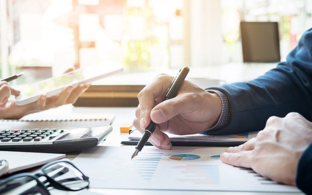 Business people reviewing financial documents with fountain pen