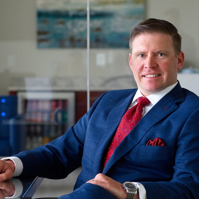 James Walsh wearing suit sitting at conference table